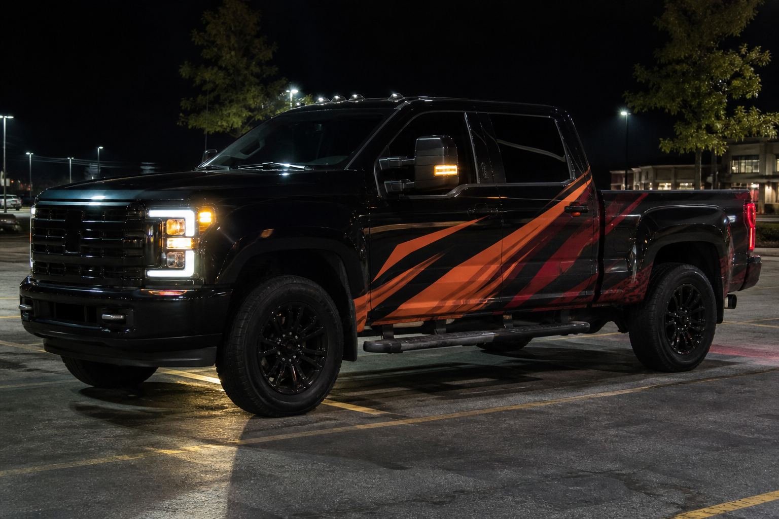 Black work truck with orange and crimson wrap graphics at night